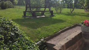 Ein Picknickunterstand mit Bank, umgeben von gepflegtem Rasen und Hecken.