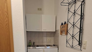 Eine kleine Küche mit weißen Schränken, einem Spülbecken und einer Arbeitsplatte.