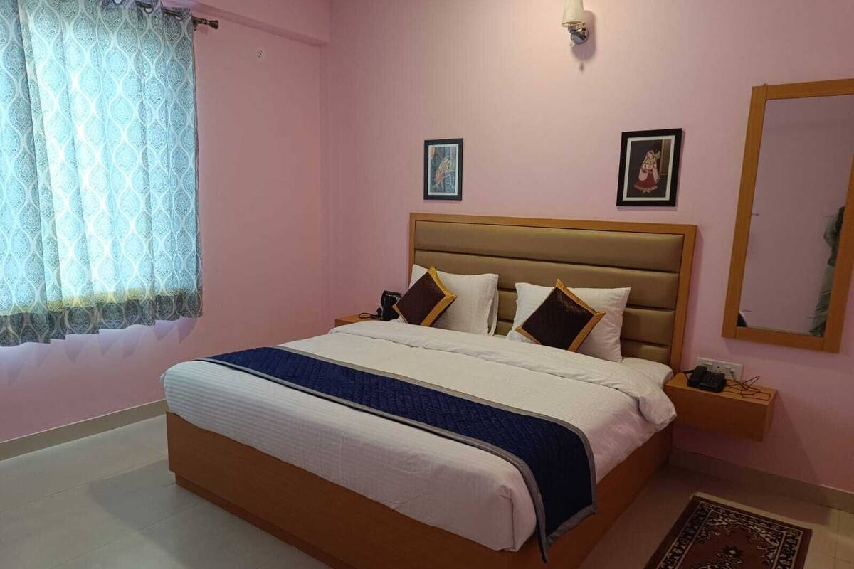 Een slaapkamer met een groot bed, een nachtkastje, een spiegel en twee prenten in lijsten aan de muur.