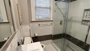 Une salle de bain moderne avec une douche à parois de verre, un grand lavabo et des toilettes.
