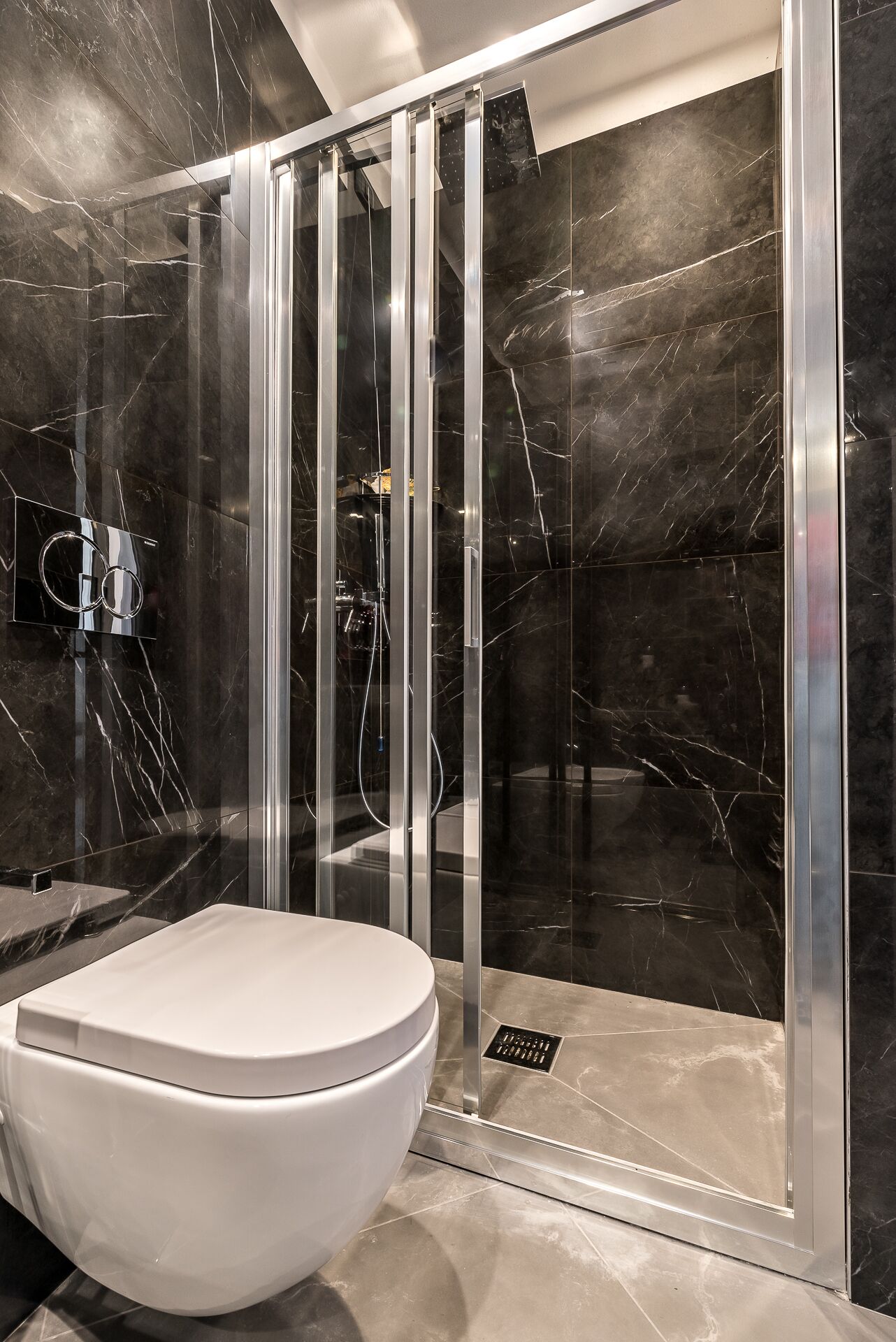 Ein modernes Badezimmer mit einer Duschkabine, einer weißen Toilette und Marmorwänden.