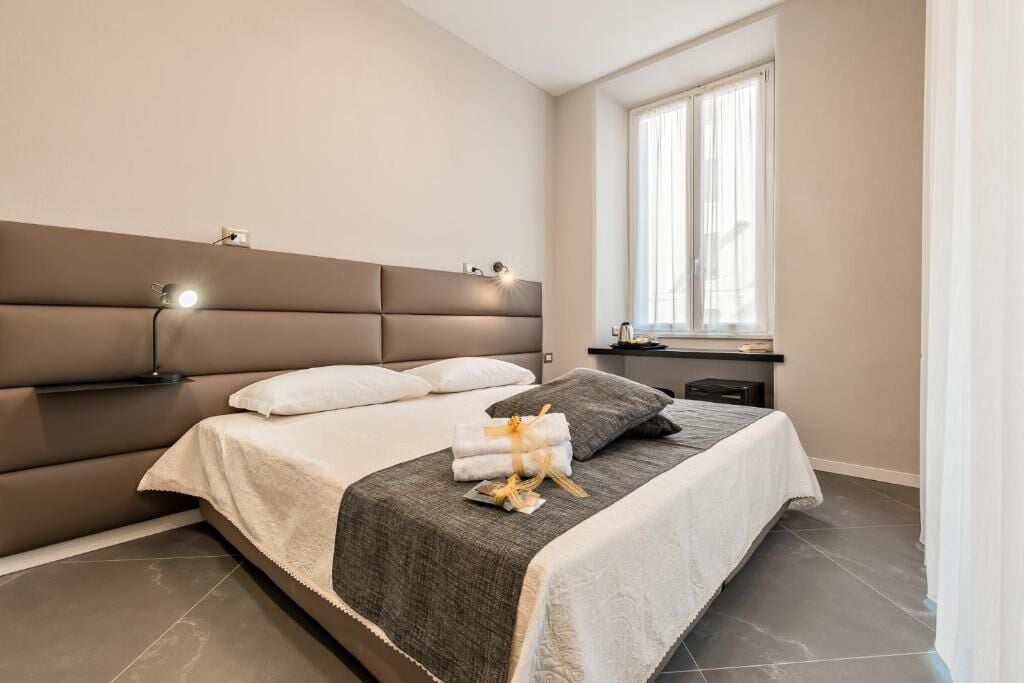 Ein modernes Schlafzimmer mit einem großen Bett, einem Nachttisch, einem Beistelltisch und einem Fenster mit Vorhängen.