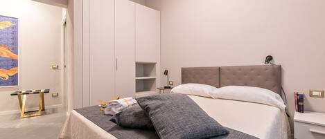Quarto com cama, mesas de cabeceira, guarda-roupa e um quadro na parede.