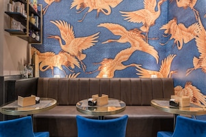 Interior de restaurante con pared estampada, asientos de cuero y mesas redondas.