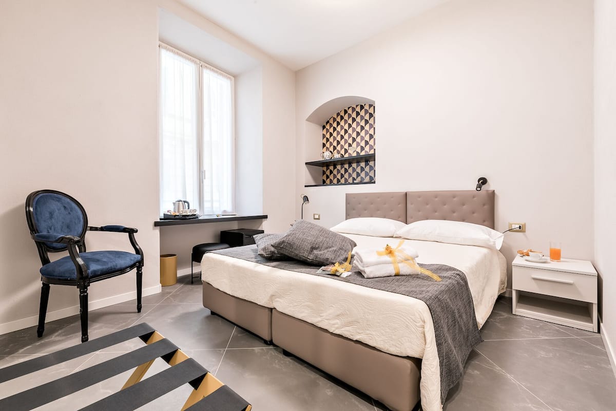 Een slaapkamer met een bed, een stoel, een bureau en een raam.