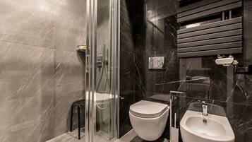 Une salle de bain moderne dotée d’une douche à parois de verre, de toilettes et d’un bidet.