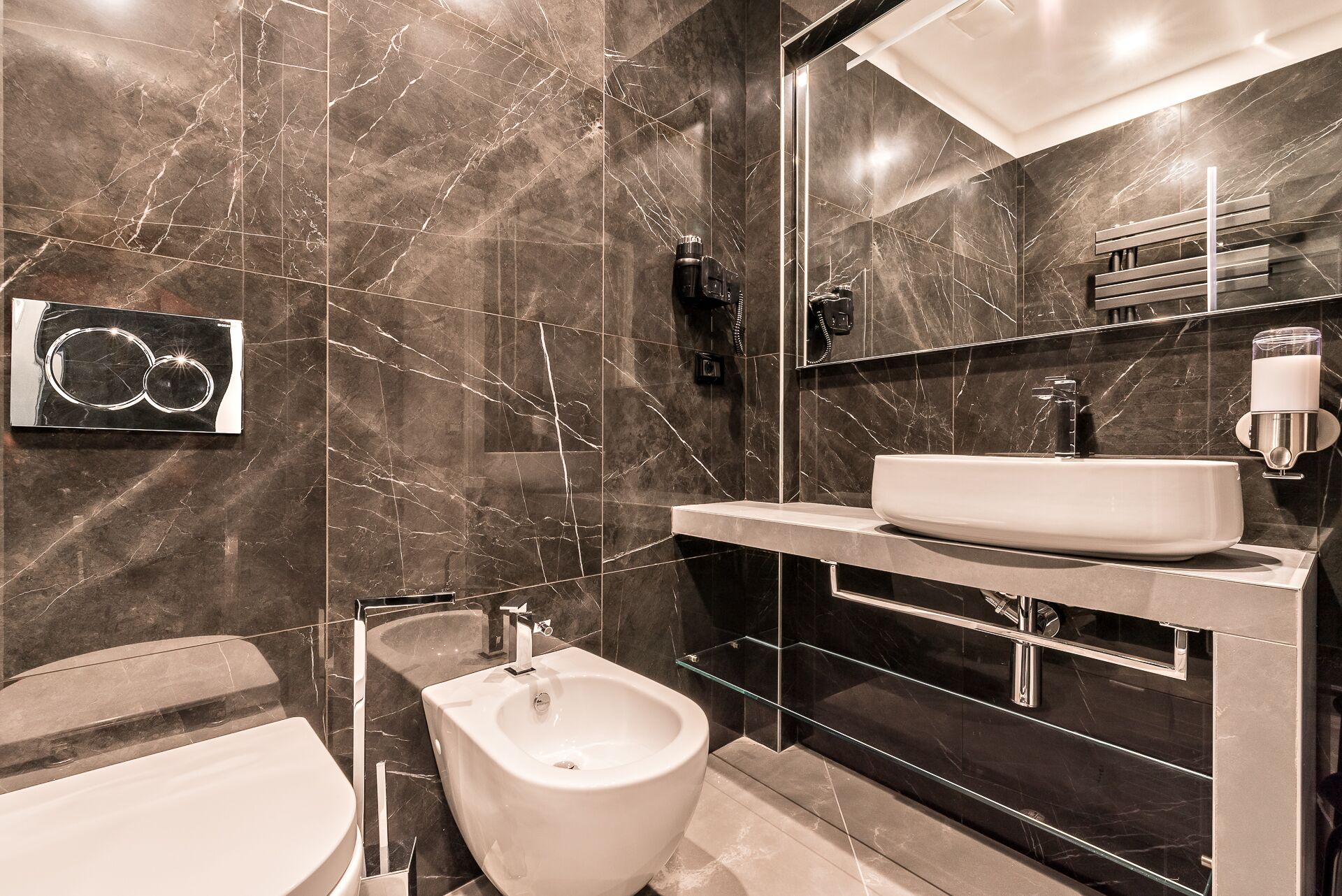 A modern bathroom with a large mirror, a white sink, and a bidet.