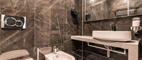 A modern bathroom with a large mirror, a white sink, and a bidet.