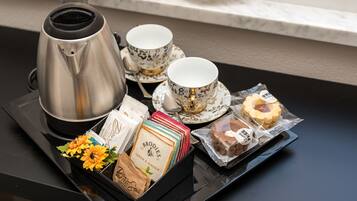 Un plateau avec une cafetière, des tasses à thé, une fleur et des en-cas emballés.
