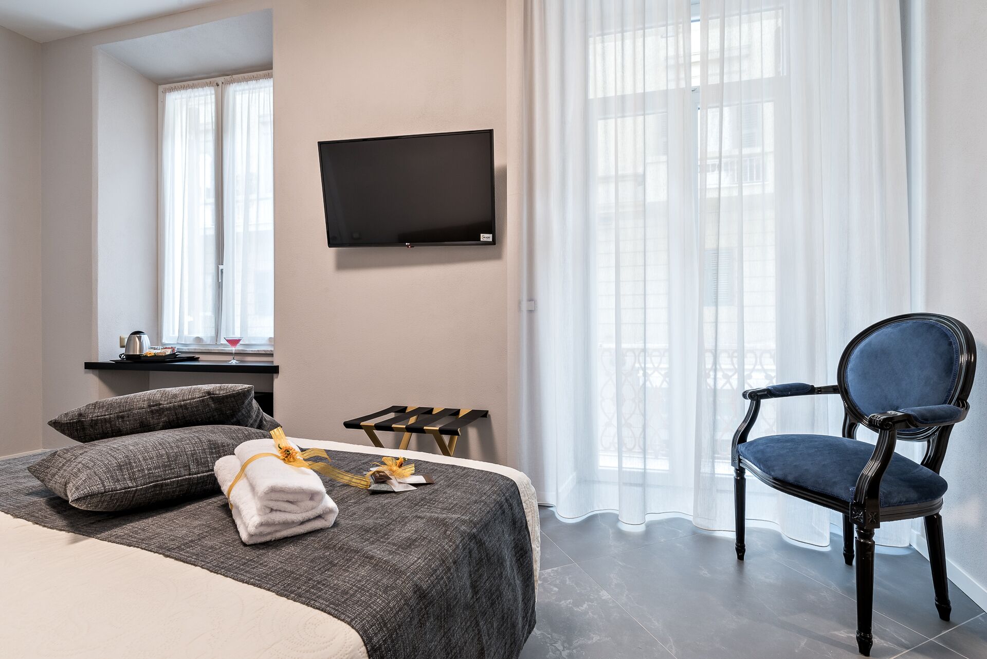 Ein Hotelzimmer mit Bett, Sessel, Fernseher und einem Fenster mit Vorhängen.
