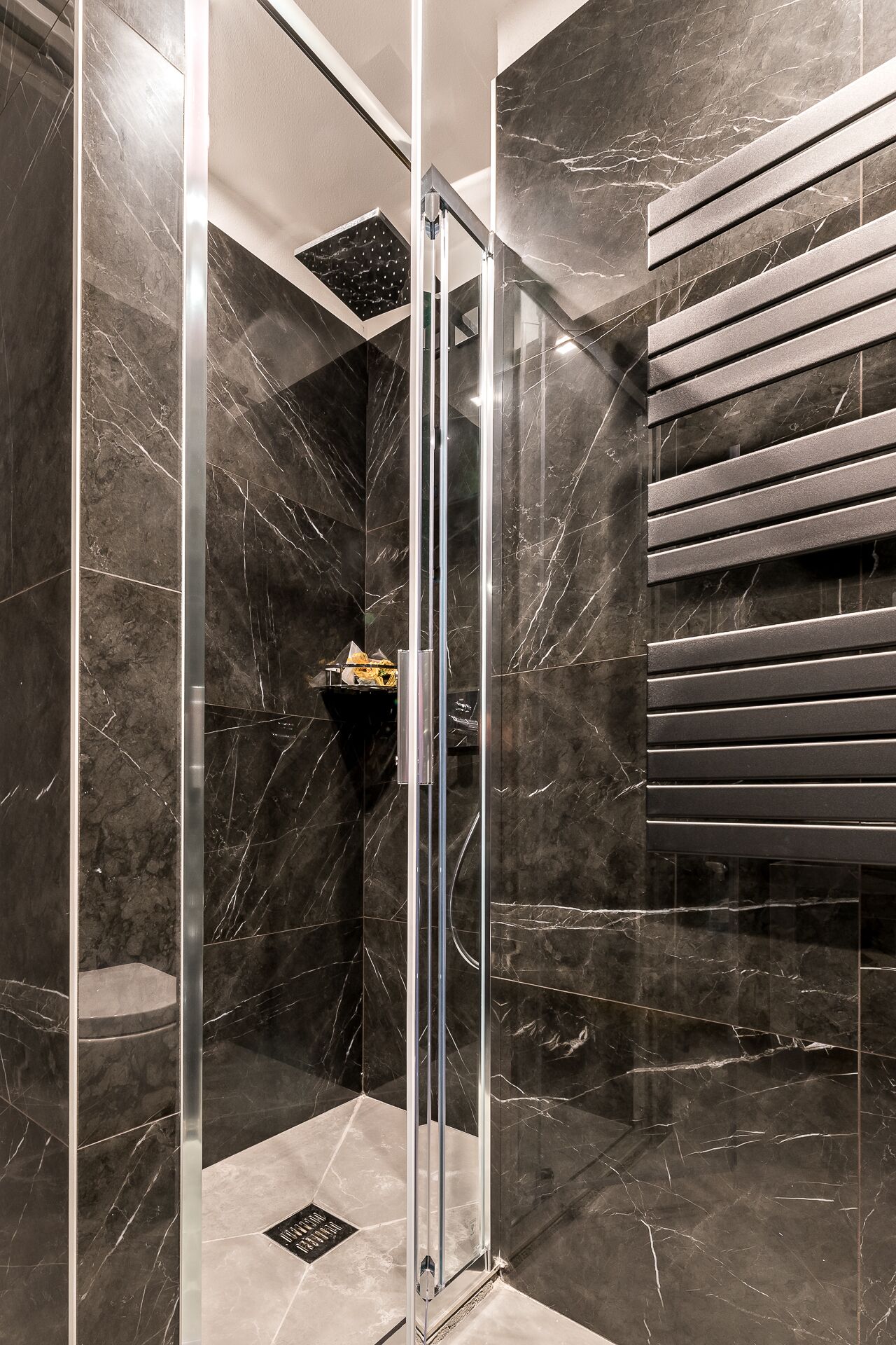 A modern bathroom with a glass-enclosed shower, marble walls, and a built-in bench.