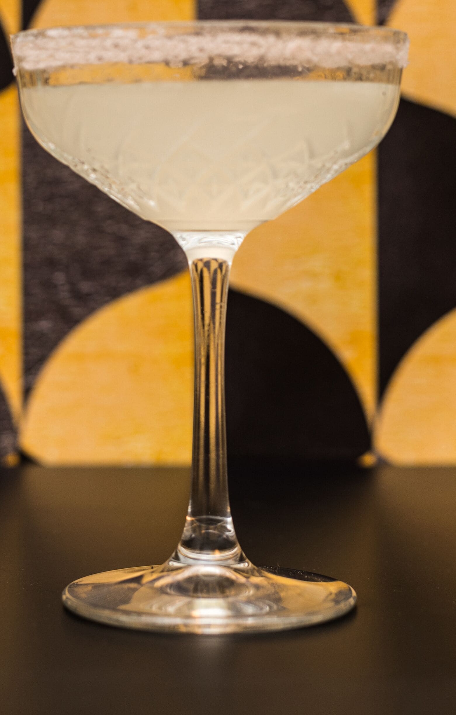A clear glass with a thick base and a wide rim, placed on a reflective surface.