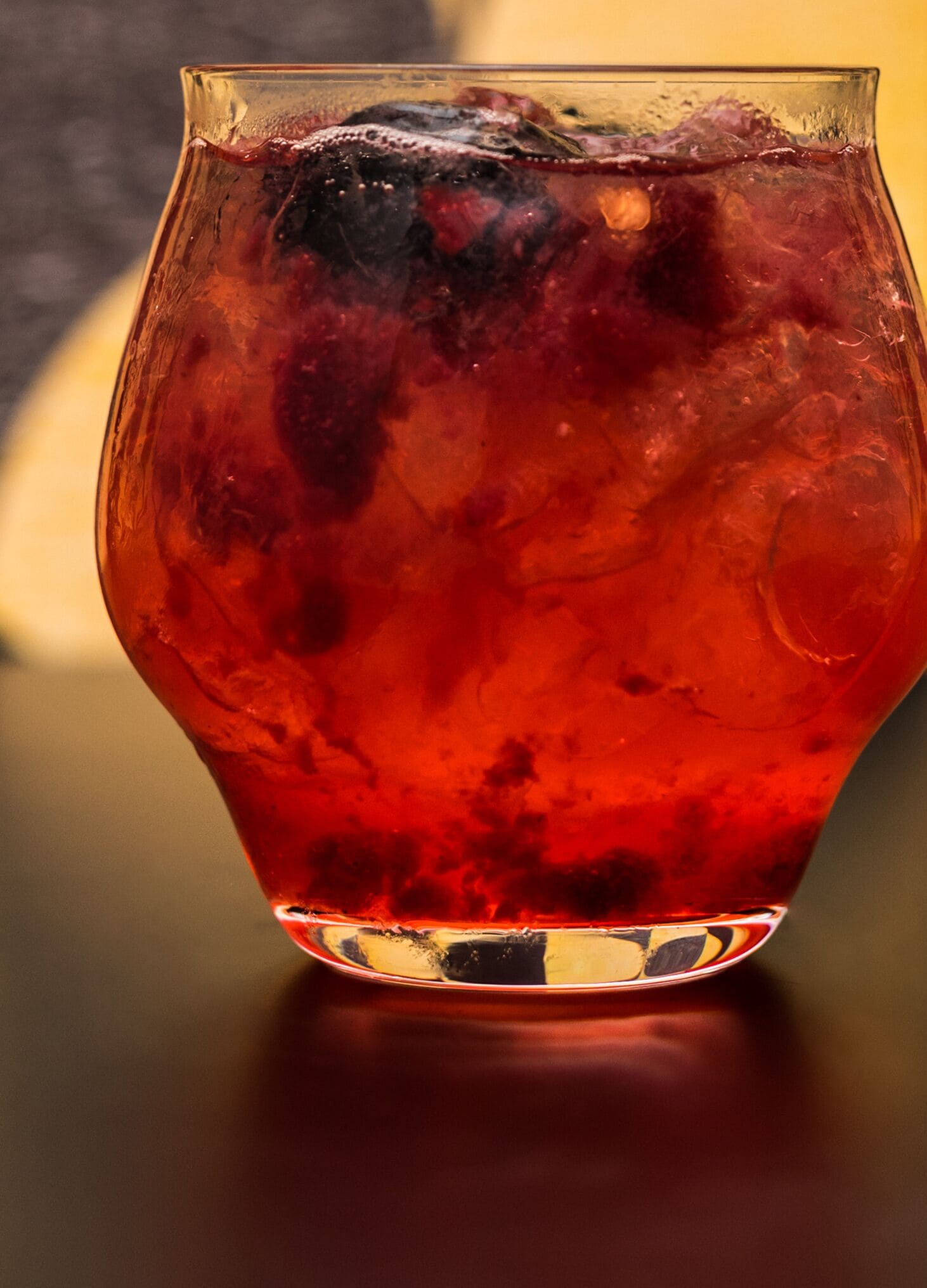 Un vaso con líquido rojo y cubitos de hielo.