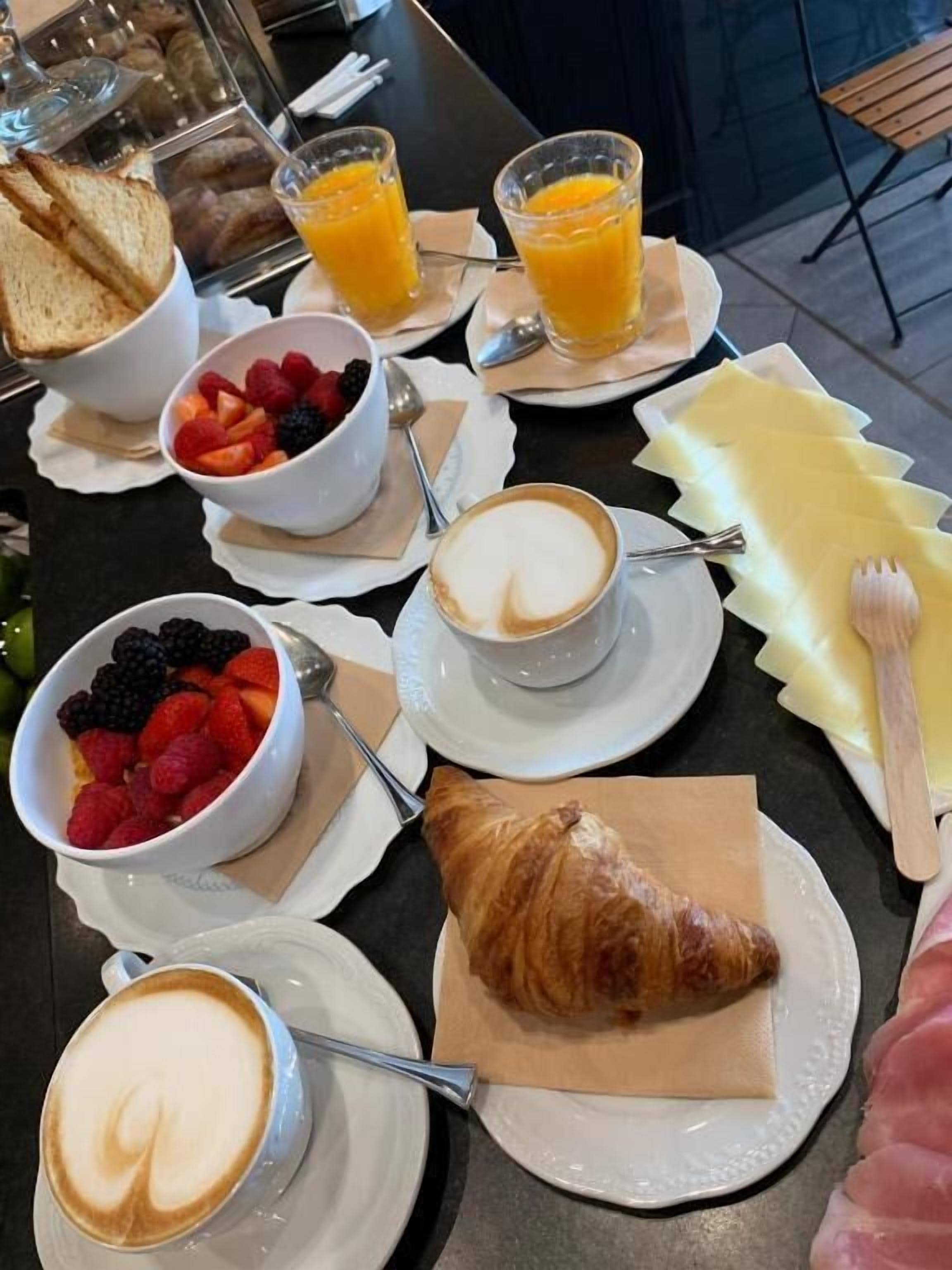 Frühstückstisch mit Croissants, Obstschalen, Kaffee und Orangensaft.