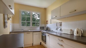 Een keuken met witte kasten, een vaatwasser, een magnetron, een broodrooster en een waterkoker.