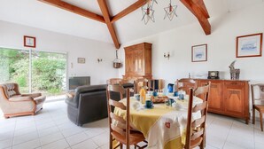 A dining area with a wooden table set for four, surrounded by wooden chairs. A wooden cabinet and a television are visible in the background. - Les Portes en Ré, house with garden for 7 (Les Portes-en-Ré)