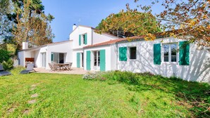 A white house with green shutters, a patio with outdoor furniture, and a grassy yard. - Les Portes en Ré, house with garden for 7 (Les Portes-en-Ré)