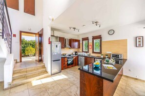 Una cocina moderna con una isla central, electrodomésticos de acero inoxidable y armarios de madera.