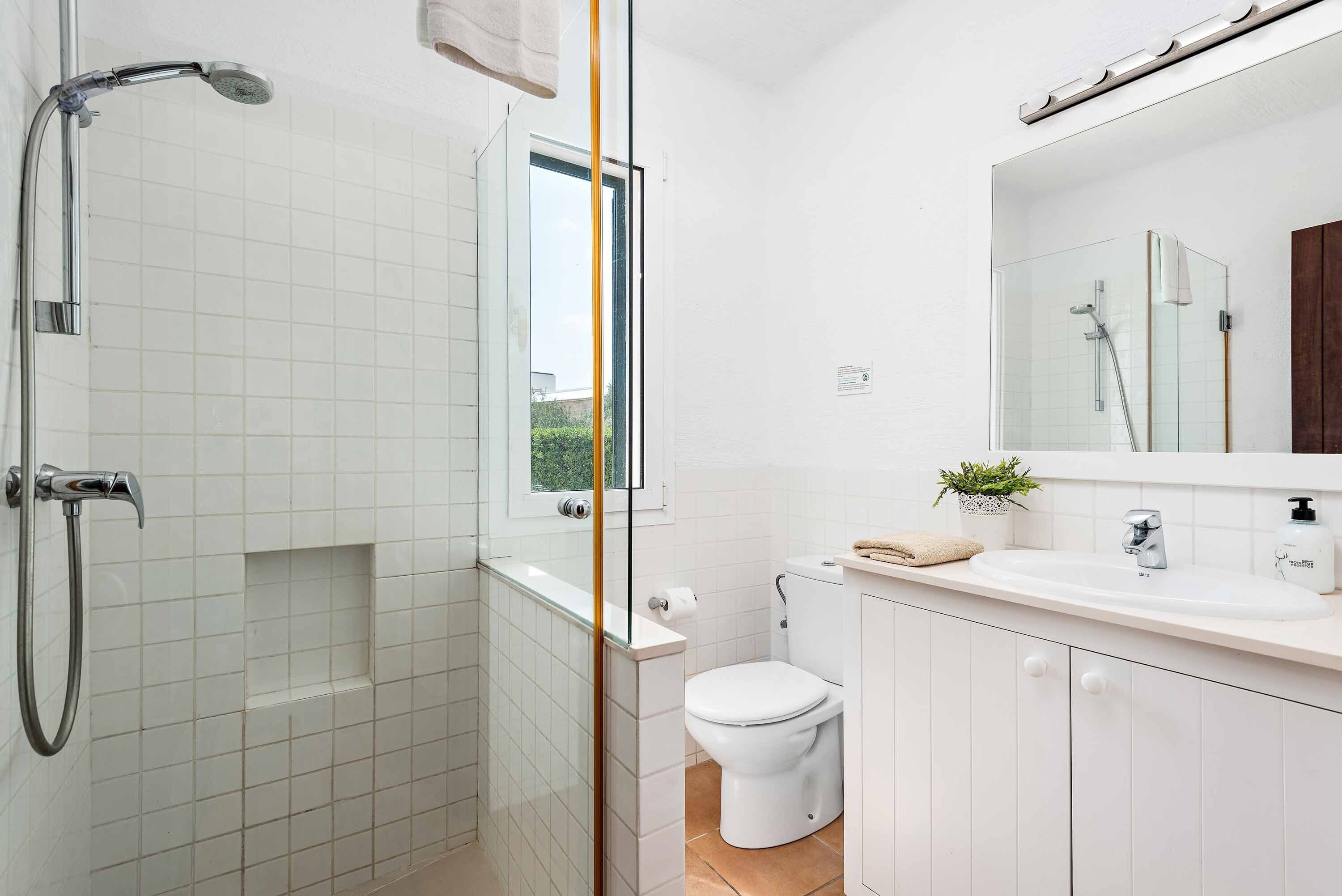 A modern bathroom with a glass-enclosed shower, a white toilet, and a sink with a mirror above it.