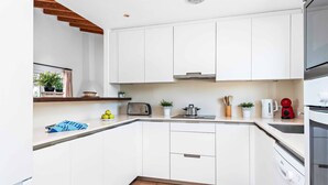 A modern kitchen with white cabinets, a countertop, a toaster, a kettle, and a coffee maker. - Bini Rosa - Five Bedroom Villa, Sleeps 10 (Binibeca)