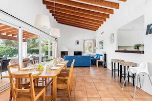 Enjoy meals in this spacious dining area with a wooden table and chairs, surrounded by a high ceiling and large window.