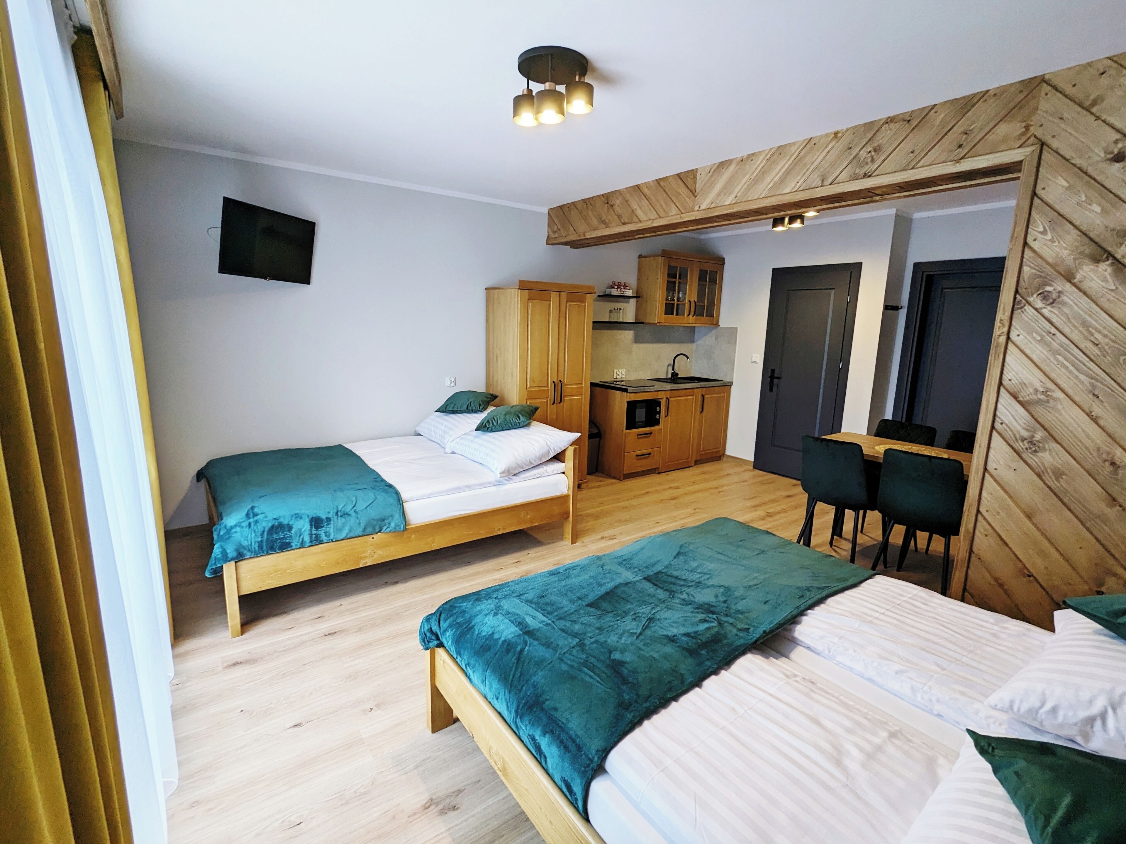 A room with two beds, a kitchenette, and a dining area.