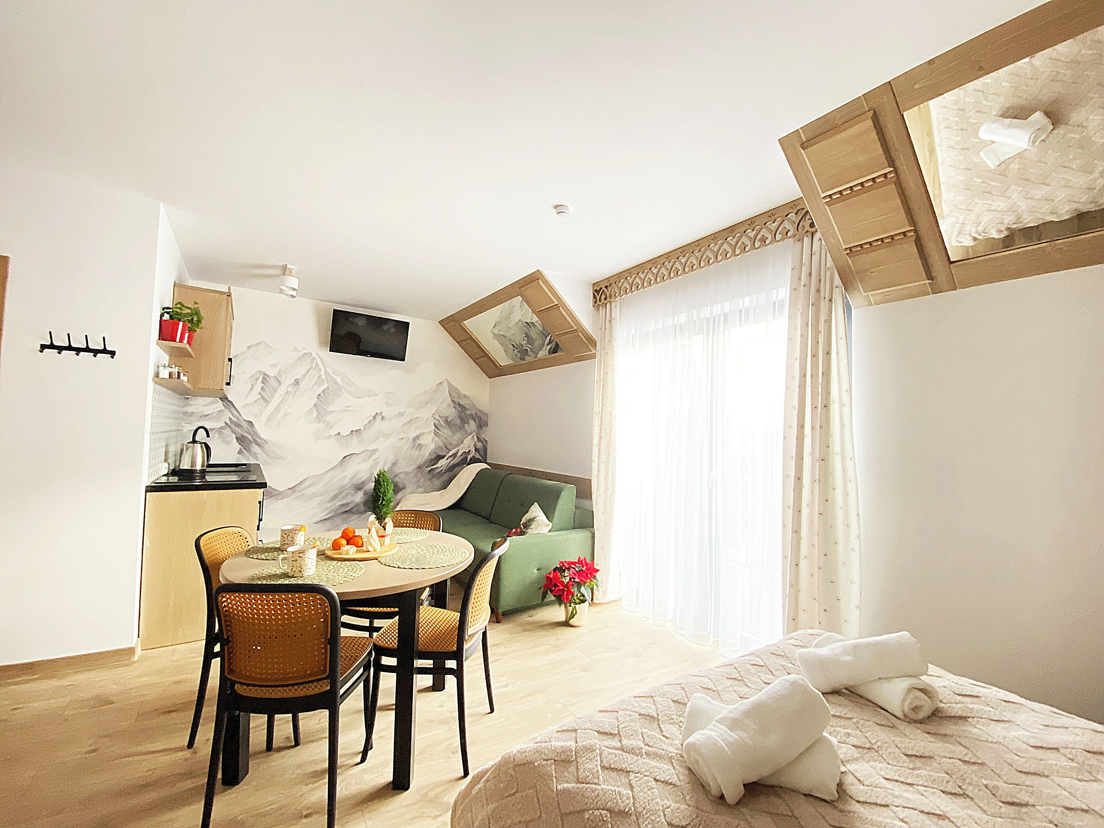 A cozy hotel room with a dining area, a sofa, and a bed with towels.