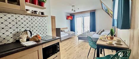 Una habitación de hotel compacta con kitchenette, zona de comedor y cama.