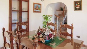 Un coin repas avec une table à plateau de verre, des chaises en bois et un arrangement floral en guise de décoration centrale.