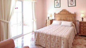 Une chambre à coucher avec un lit, deux tables de chevet, une chaise et une fenêtre avec des rideaux.