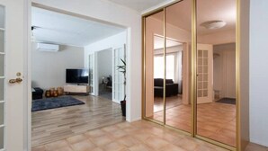 Een ruime woonkamer met een grote schuifpui naar een balkon, een flatscreen televisie en een zithoek.
