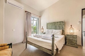 Une chambre à coucher avec un lit, une table de chevet, une chaise et une fenêtre avec des rideaux.