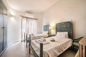 Een hotelkamer met twee bedden, een kledingkast, een airconditioner, een bedlampje en een gordijn.