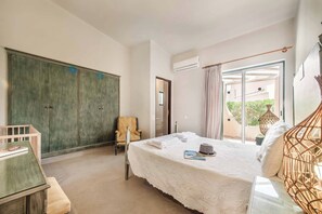 A bedroom with a bed, a chair, a wardrobe, and an air conditioning unit.