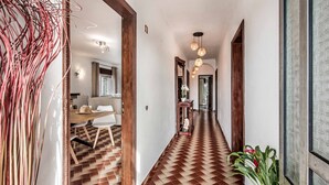 Un pasillo con suelo estampado, puertas de madera e iluminación colgante.