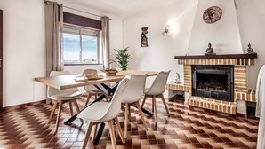 Comedor con suelo de ladrillo, mesa de madera y sillas blancas.