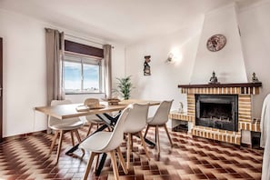 Comedor con suelo de ladrillo, mesa de madera y sillas blancas.