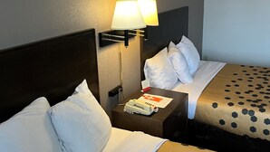 Une chambre d’hôtel avec deux lits, une table de chevet avec une lampe et un panneau accroché au mur.