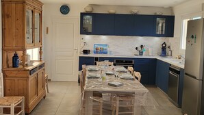 Een moderne keuken met blauwe kastjes, een houten eettafel en een koelkast van roestvrij staal.