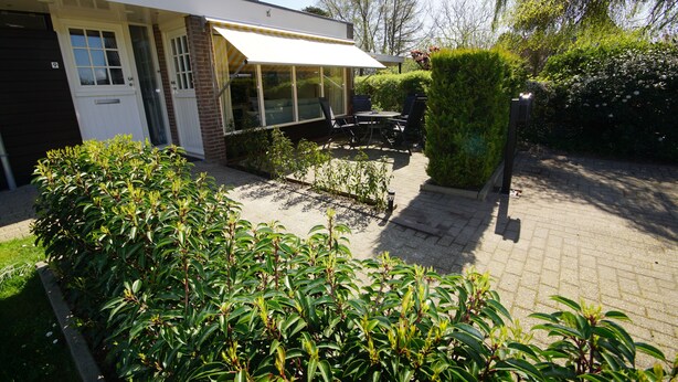 Ein modernes Haus mit überdachter Terrasse, Ziegelaußenwand und gepflegtem Garten.