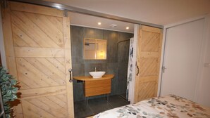 Ein Schlafzimmer mit einem Holzschrank, einem Nachttisch mit Waschbecken und einem Bett mit blumigem Überwurf.