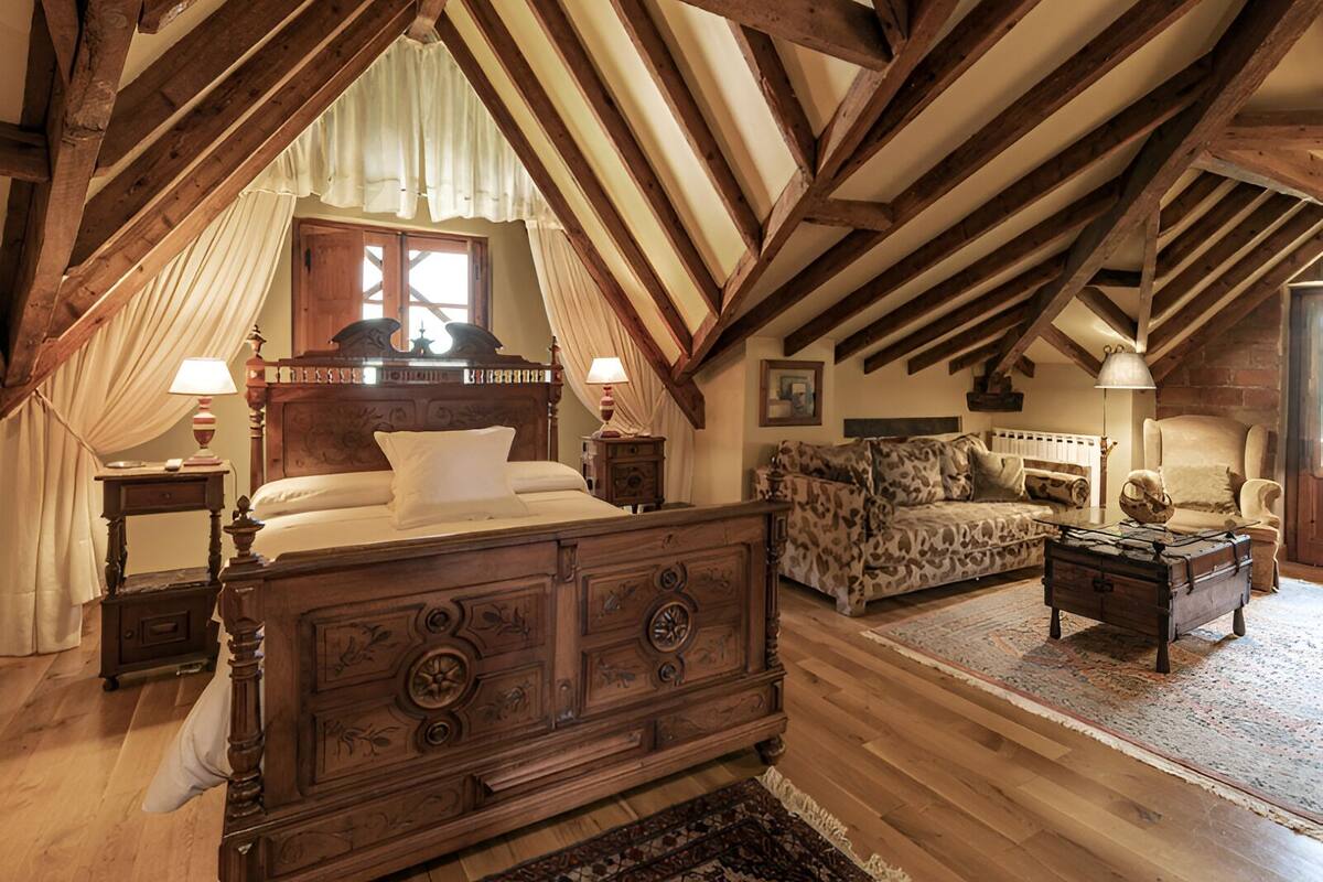 A bedroom with a wooden bed, a sofa, a chest of drawers, and a small table.