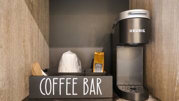 Disposição de um bar de café com uma cafeteira Keurig, um sachê de café e um saco de café.