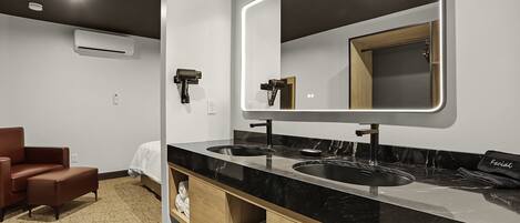 A modern bathroom with a black marble vanity, dual sinks, and a large mirror.