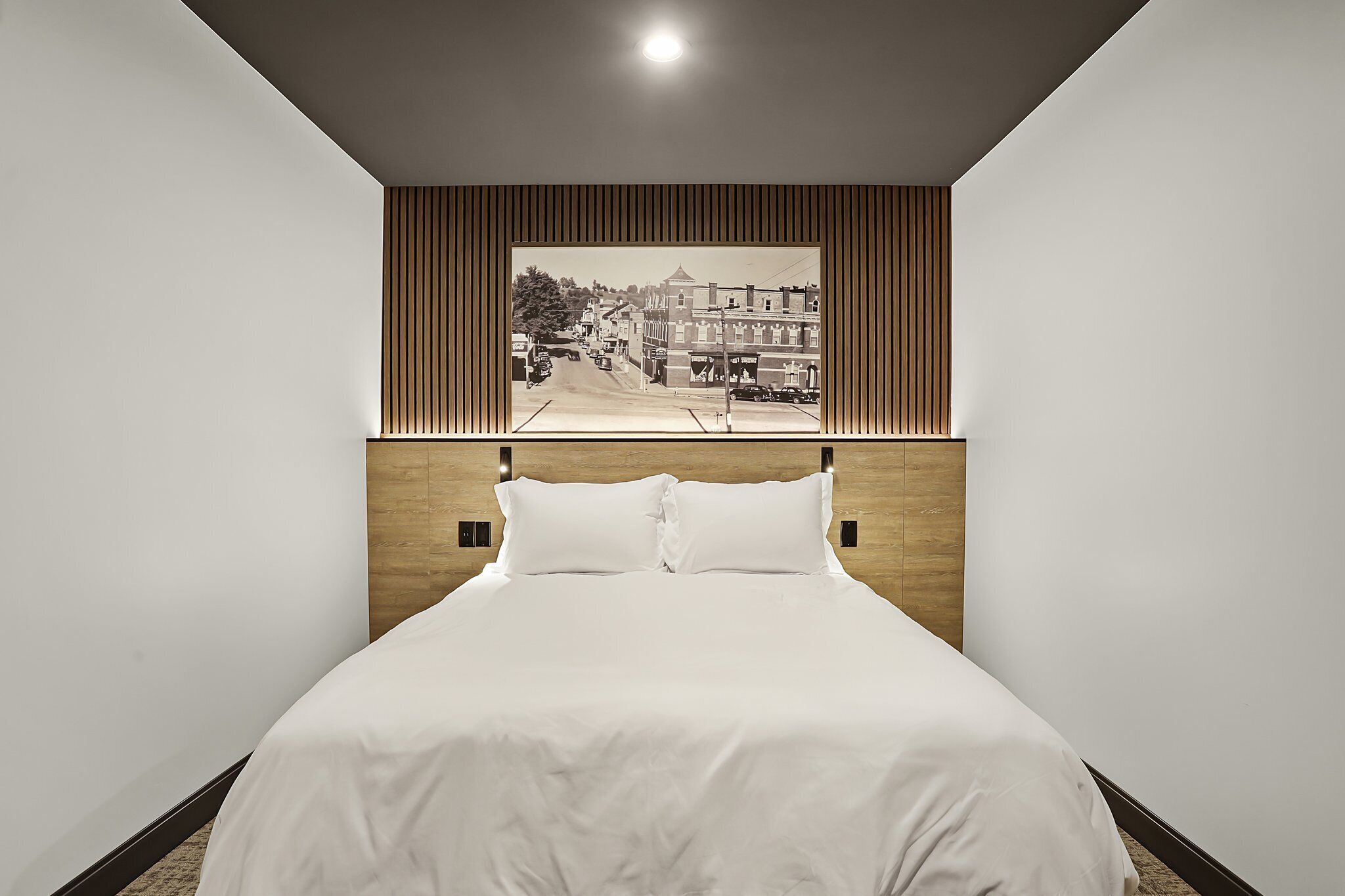 Un lit bien fait, avec une tête de lit ornée d’un panneau en bois vertical.