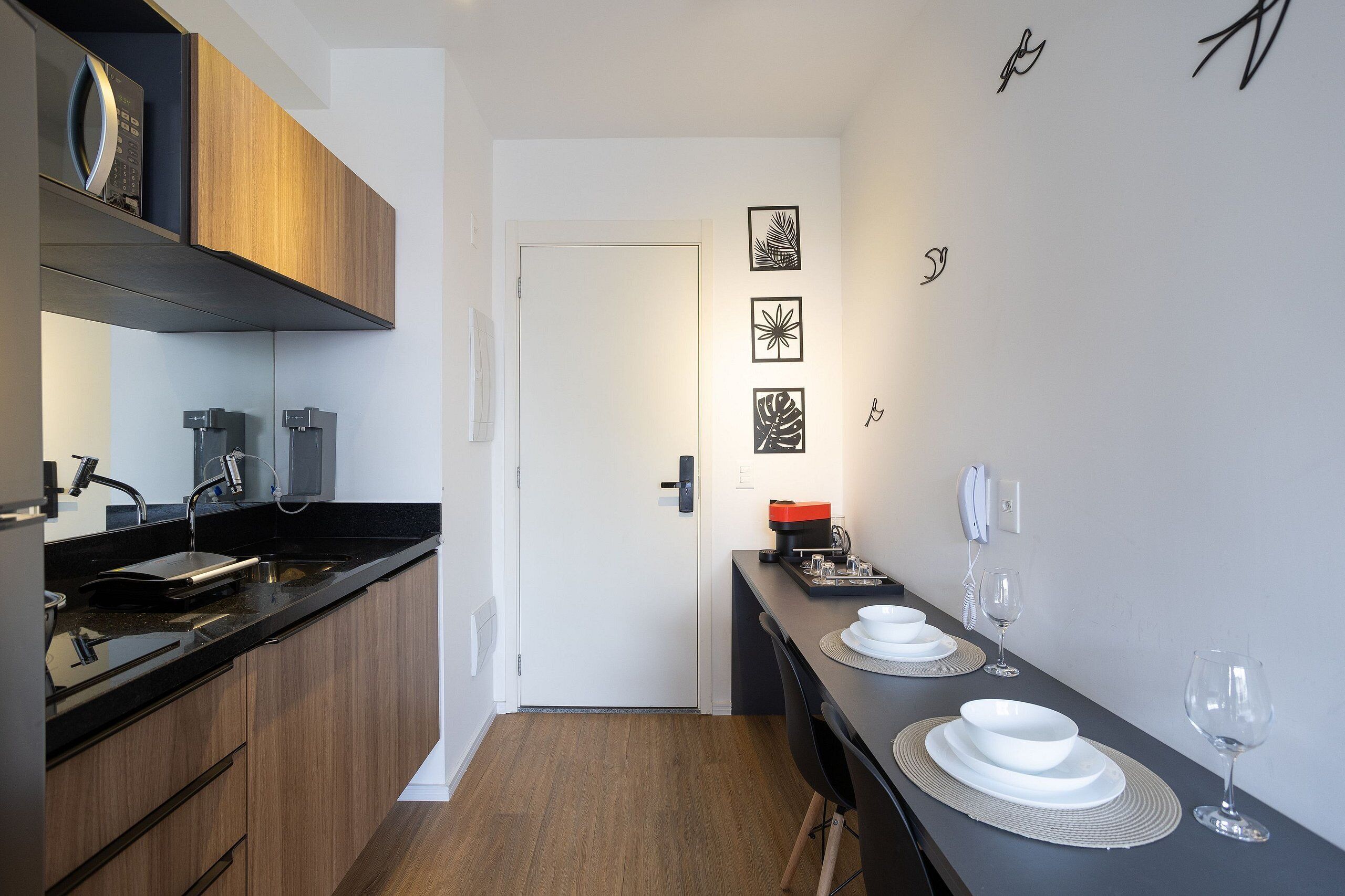 A modern kitchen with wooden cabinets, a black countertop, and a dining area with a black table and white plates.