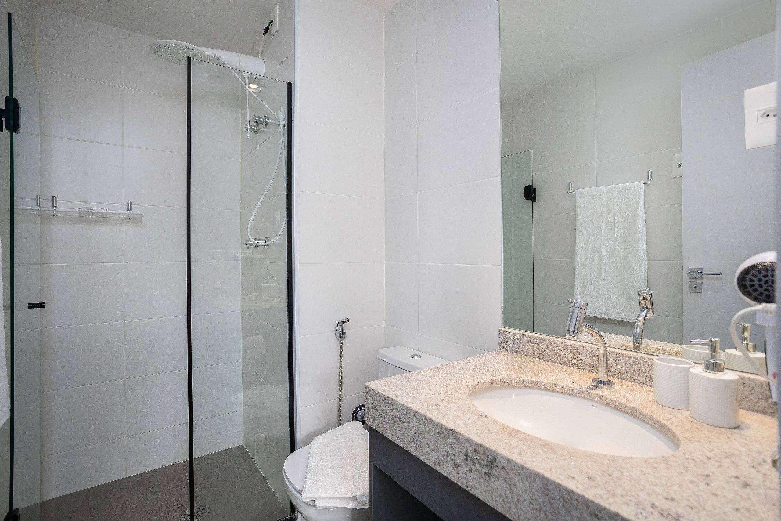 A modern bathroom with a glass-enclosed shower, a white sink, and a large mirror.