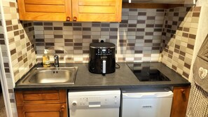 Een keuken met een koffiezetapparaat, vaatwasser en een betegelde achterwand.