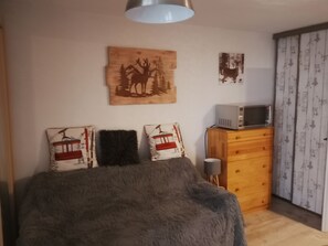 Une chambre à coucher comprenant un lit, une commode, un four à micro-ondes et des œuvres d’art murales.