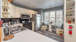 Een moderne keuken met witte kasten, roestvrijstalen apparatuur en een raamzitje.